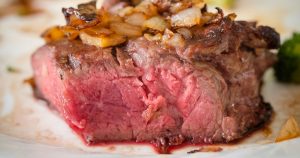 a juicy steak with a pink center and caramelized onions on top