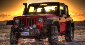 Red Jeep on a beach at sunset