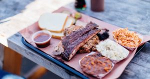 a tray of bbq on an outdoor wooden table