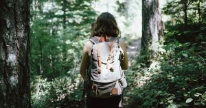 a women with a hiking backpack walking on a trail